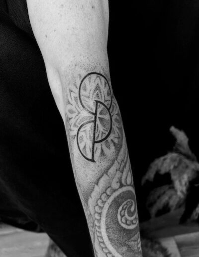 Schwarz-weiß Fotografie eines Unterarms mit einem geometrischen Tattoo, kombiniert aus floralen Mustern und feinen Linien.